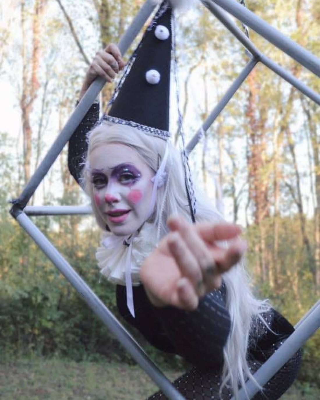 Aerial performer in a harlequin headpiece reaching out
