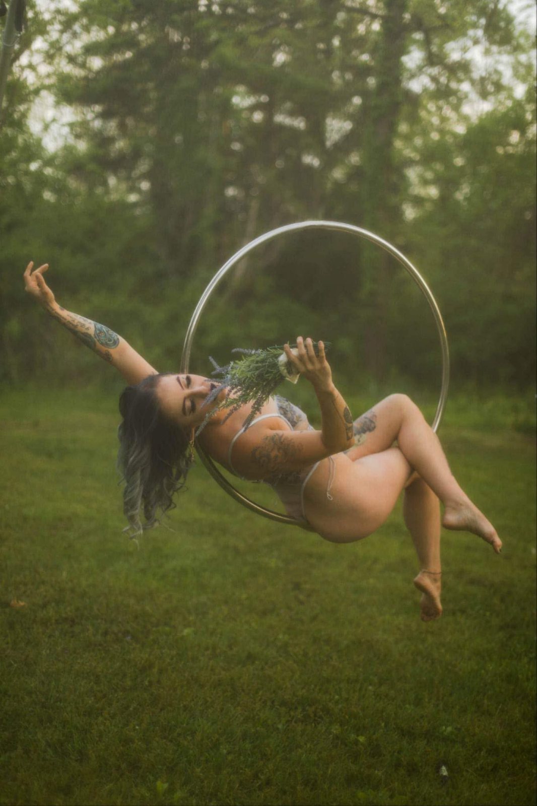 Aerial hoop performer reclining in a misty field