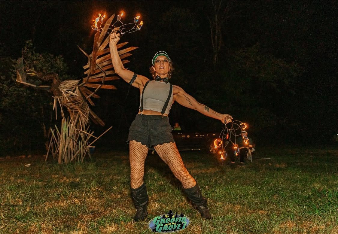 Fire performer with arms raised at a night festival