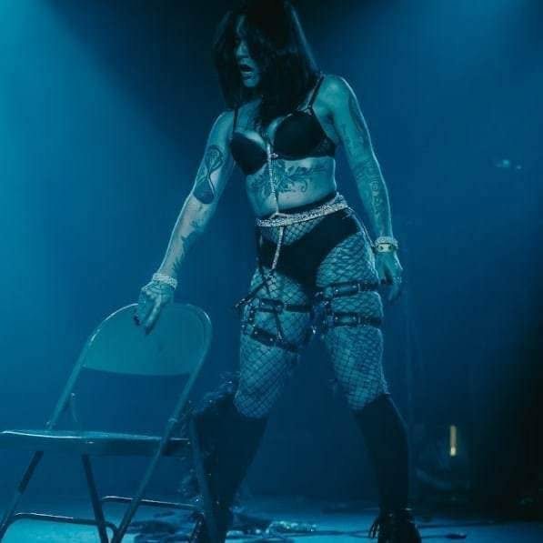 Burlesque performer in fishnets under blue light