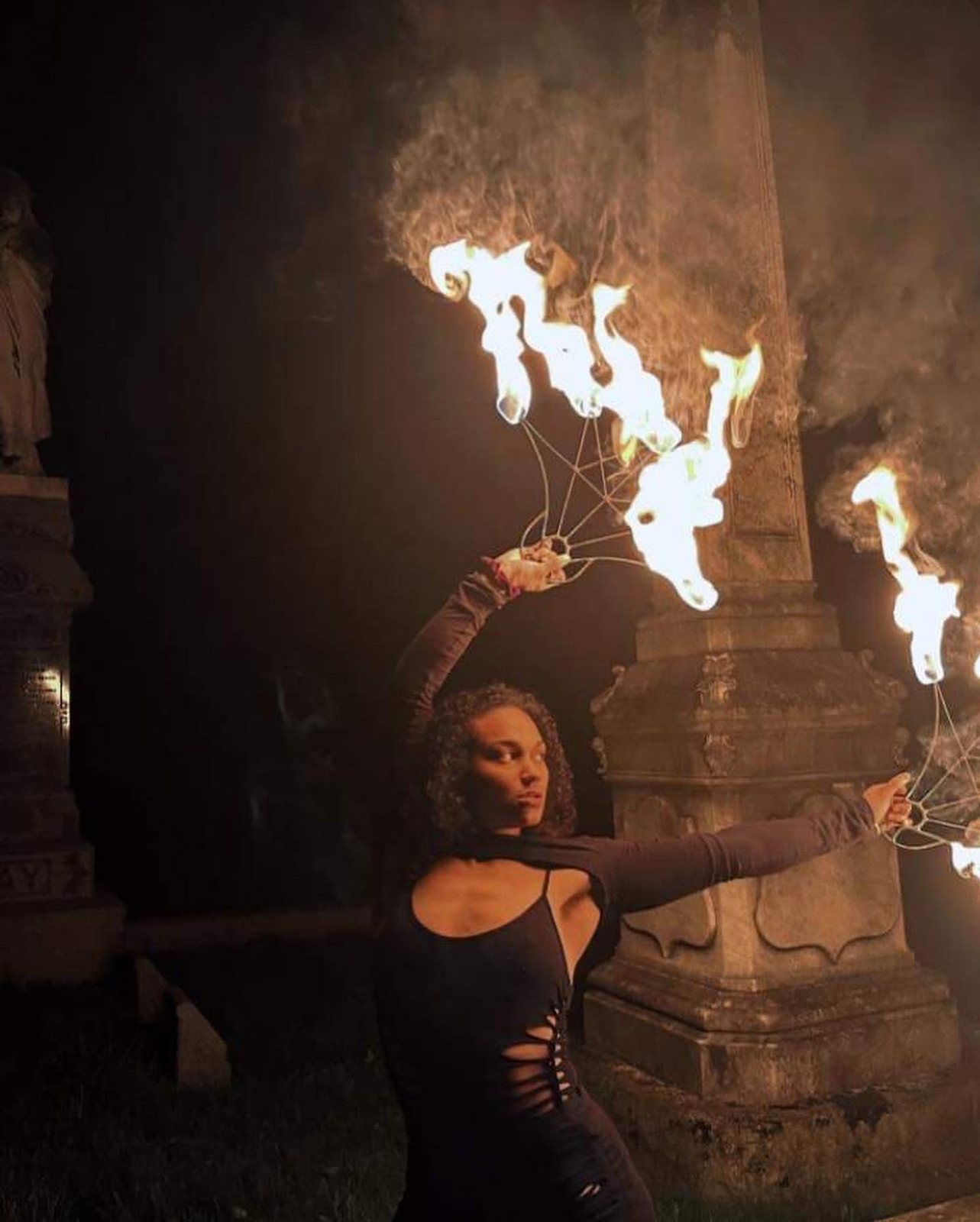 Fire fan performer before a stone tower at night